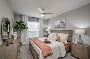 Kingwood apartment for rent - A bedroom with a large bed, a dresser, and a ceiling fan.