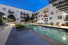 Austin apartment for rent - A modern apartment complex with a pool and a walkway.