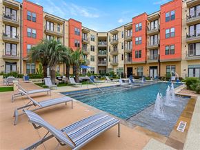 Austin apartment for rent - A pool with a fountain and sun loungers in front of apartment buildings.