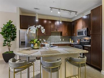 Austin apartment for rent - A kitchen with brown cabinets and a table with chairs.