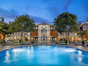 Dallas apartment for rent - A large swimming pool in front of a building with a glass facade.