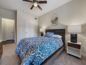 Kingwood apartment for rent - A bedroom with a bed, a ceiling fan, and a mirror on the wall.