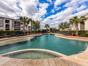 Richmond apartment for rent - A large outdoor swimming pool surrounded by palm trees and lounge chairs.