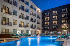 Austin apartment for rent - A swimming pool in front of apartment buildings at dusk.
