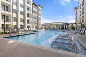 Austin apartment for rent - A large swimming pool with lounge chairs and a building in the background.