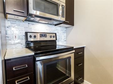 Seattle apartment for rent - A black stove top oven with a digital display is in a kitchen.