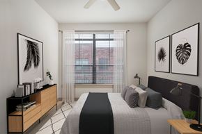 Houston apartment for rent - A bedroom with a bed, a ceiling fan, and two framed pictures on the wall.