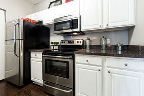 Plano apartment for rent - A black refrigerator is in a kitchen with white cabinets.