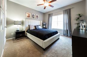 Plano apartment for rent - A bedroom with a large bed and a ceiling fan.
