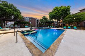 Plano apartment for rent - A swimming pool surrounded by trees and a building in the background.
