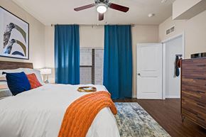 Austin apartment for rent - A bedroom with a white bed and a ceiling fan.