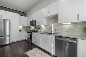 Austin apartment for rent - A modern kitchen with white cabinets and stainless steel appliances.