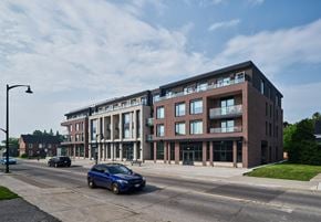 Stittsville apartment for rent - A blue car is driving on a road in front of a large building.
