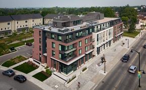 Stittsville apartment for rent - A modern red brick building with a balcony on the top floor.