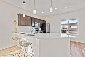 Deforest townhouse for rent - an open kitchen with a large island with bar stools at The Residences Apartments at Bear Tree, DeForest, WI 53532