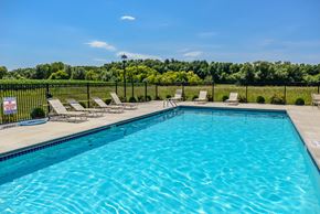 Oconomowoc apartment for rent - A swimming pool with lounge chairs and a fence.