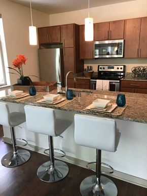 Wauwatosa apartment for rent - A kitchen with a granite countertop and white bar stools.