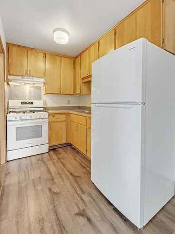 Minneapolis apartment for rent - A white refrigerator stands in a kitchen with wooden cabinets.