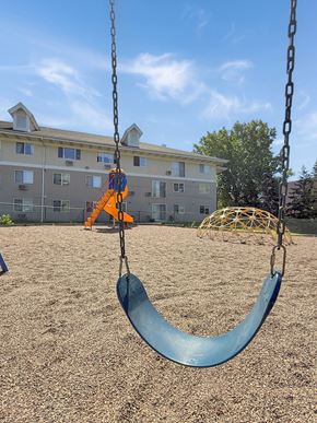 Minnetonka apartment for rent - A swing set in a playground with a blue slide.