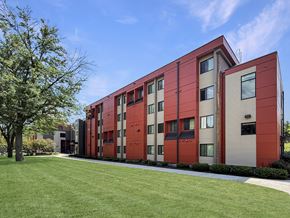 Saint Paul apartment for rent - A red and beige building with a tree in front.
