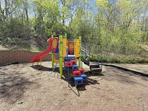 St. Paul apartment for rent - A playground with a red slide, a blue and yellow climbing frame, and a red and blue climbing wall.