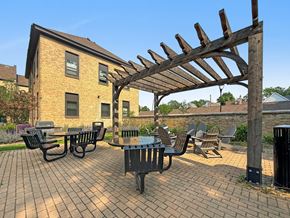Minneapolis apartment for rent - A patio with a table and chairs under a wooden pergola.