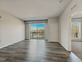 Minneapolis apartment for rent - A spacious room with wooden flooring and a view of a fenced area outside through a sliding glass door.