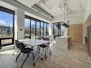 Minneapolis apartment for rent - A conference room with a long table and chairs, a kitchenette, and a view of the outside through large windows.