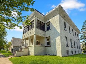 Minneapolis apartment for rent - A white building with a triangular roof and a balcony on the second floor.