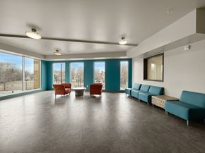 Minneapolis apartment for rent - A spacious community lobby with a long couch and a table with chairs.