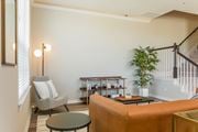Denton townhouse for rent - A living room with a grey chair, a brown sofa, a green plant, and a wooden coffee table.