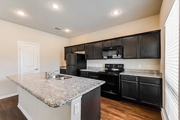 Forney townhouse for rent - a kitchen with black appliances and granite counter tops