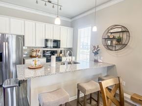 Rosharon townhouse for rent - A kitchen with a refrigerator, microwave, and bar stools.