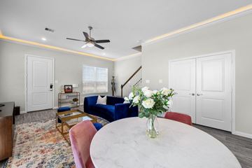 Humble townhouse for rent - A living room with a white table and a vase of white flowers on it.