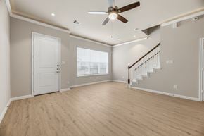 Atascocita townhouse for rent - A spacious room with a staircase and a ceiling fan.