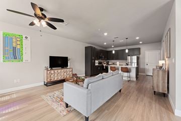 Denton townhouse for rent - A living room with a grey couch and a ceiling fan.