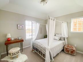 Rosharon townhouse for rent - A bedroom with a white bed and a small table with a lamp and a red ball on it.