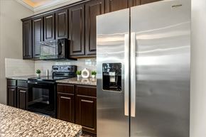 Kingwood townhouse for rent - A kitchen with a stainless steel refrigerator and black cabinets.
