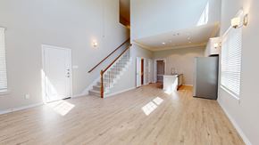 Waxahachie townhouse for rent - A spacious room with wooden floors and a staircase.