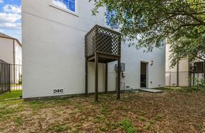 Kingwood townhouse for rent - A white building with a black gate and a tree in front.