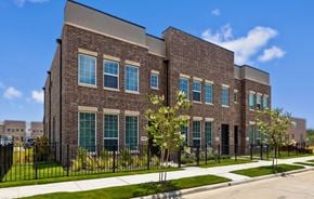 Lewisville townhouse for rent - A modern brick building with green windows and a black fence.