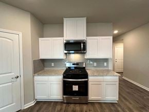 Youngsville house for rent - A kitchen with white cabinets and a black stove top oven.