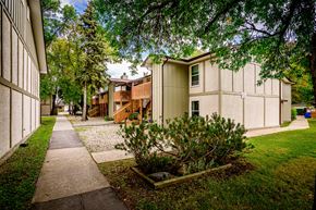 Winnipeg apartment for rent - a sidewalk between two buildings with trees and grass