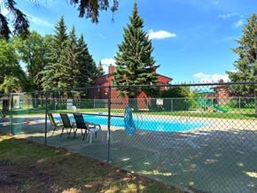 Winnipeg apartment for rent - A pool surrounded by a fence with trees in the background.