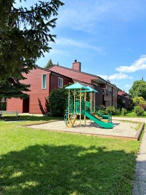 Winnipeg apartment for rent - A playground with a green slide and a red building in the background.