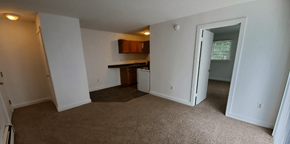 New London apartment for rent - an empty living room with a kitchen in the background