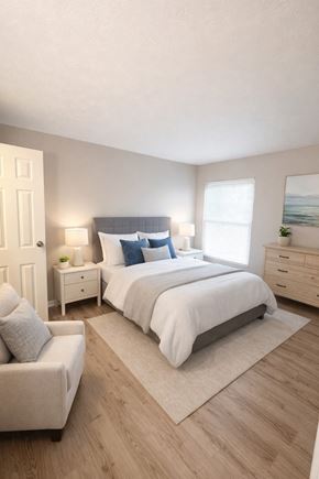 Cincinnati apartment for rent - A bedroom with a large bed, a nightstand, a chair, and a rug.
