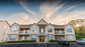 Cincinnati apartment for rent - A large, well-lit apartment complex with multiple balconies and cars parked in the driveway.