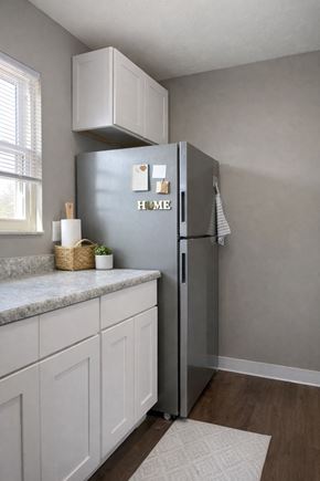 Cincinnati apartment for rent - A kitchen with a grey fridge and white cabinets.