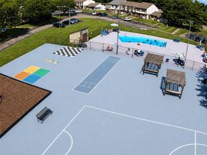 Huber Heights apartment for rent - A basketball court with a blue surface and white lines, surrounded by a fence and with a pool in the background.